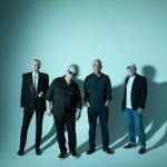 Pixies band standing against a duck egg blue backdrop